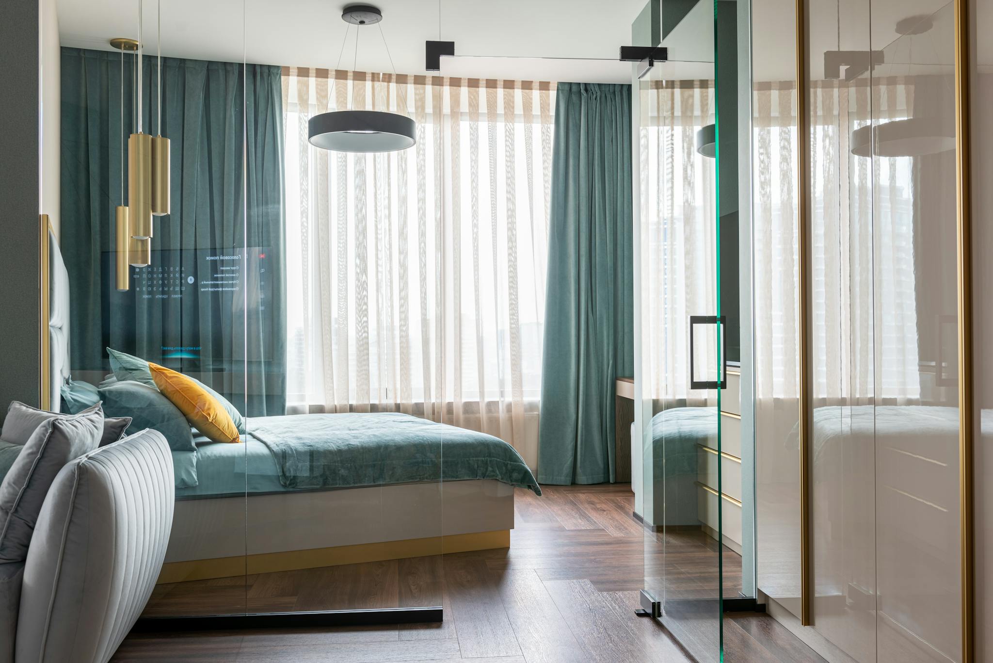 Elegant bedroom interior with modern glass walls, teal bed and decor.