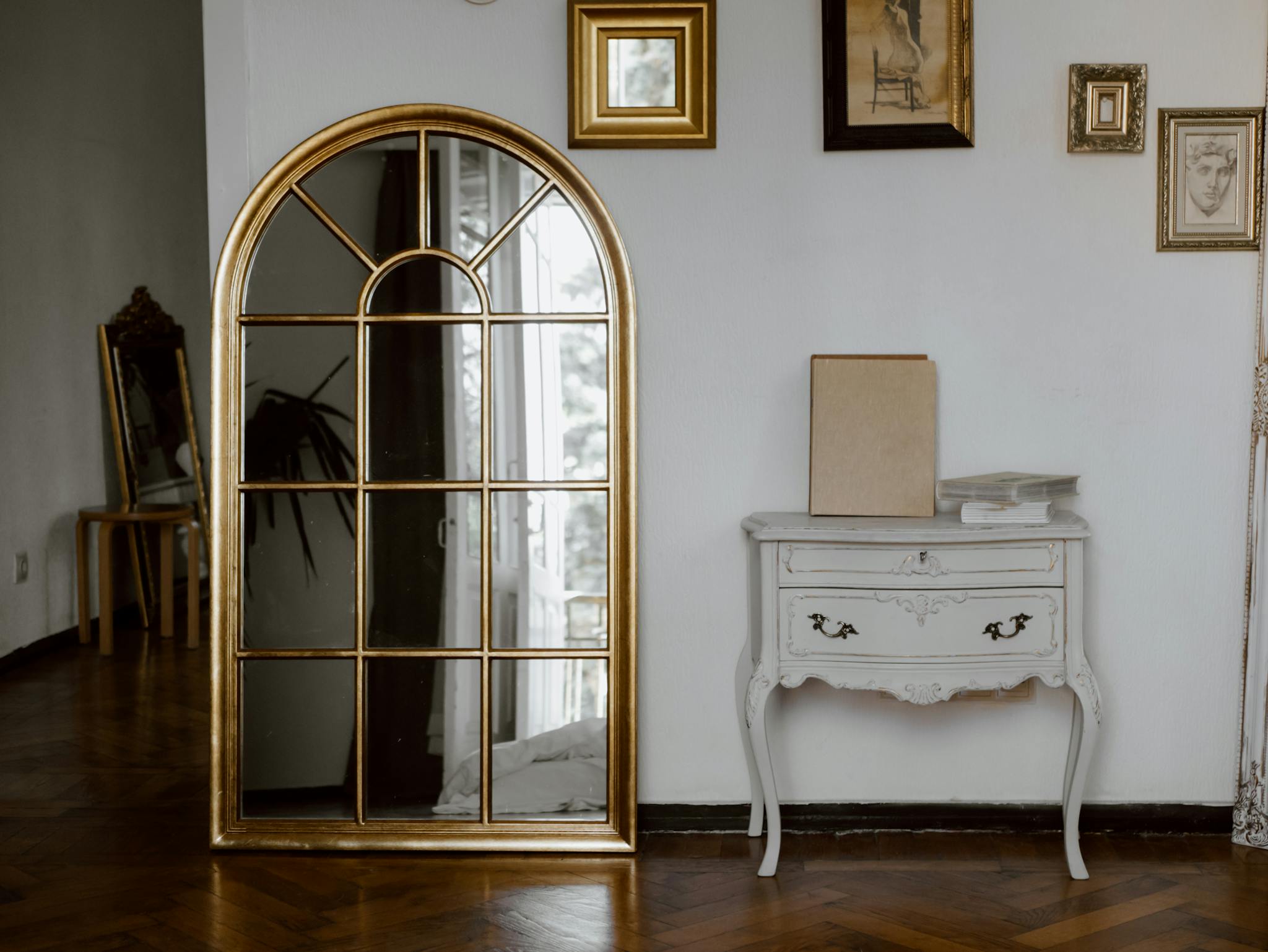 Vintage-style interior featuring a gold arched mirror and a classic white console table.